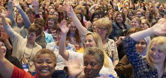 Happy crowd of teachers raising hands