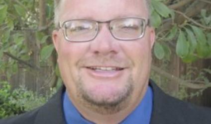 [image of headshot of Kevin Crosby, wearing a suit and tie, standing in front of tree]